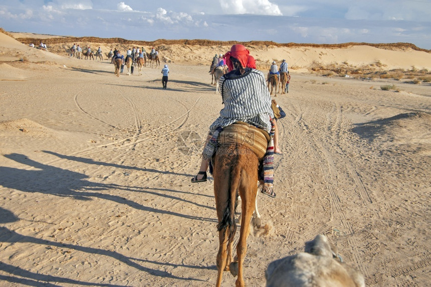沙漠中旅行骑骆驼的人图片
