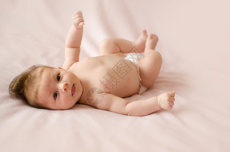 可爱的两个月大女婴躺在粉红色毯子背上的柔软裙子眼睛盯着高清图片素材