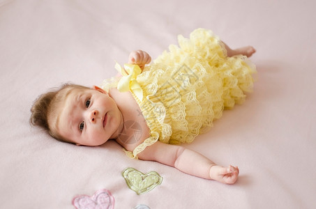 老的可爱两个月大女婴躺在粉红色毯子背上部快乐的粉色的高清图片素材