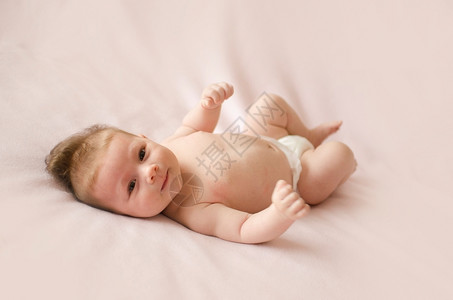 孩子可爱的两个月大女婴躺在粉红色毯子背上裙脸背部高清图片素材