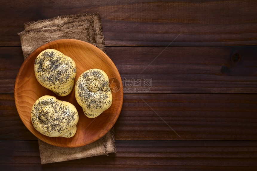 包子最佳烘烤木板上的自制种子面包卷用自然光照在黑木头的上面图片