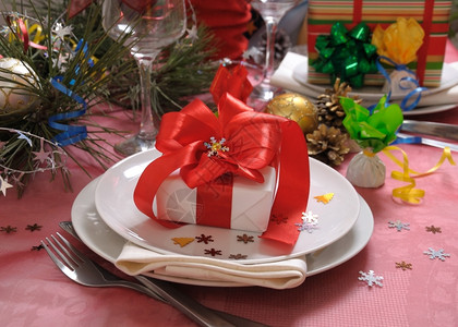 蜡烛圣诞礼物和红弓在圣诞节的日餐桌上子时尚图片