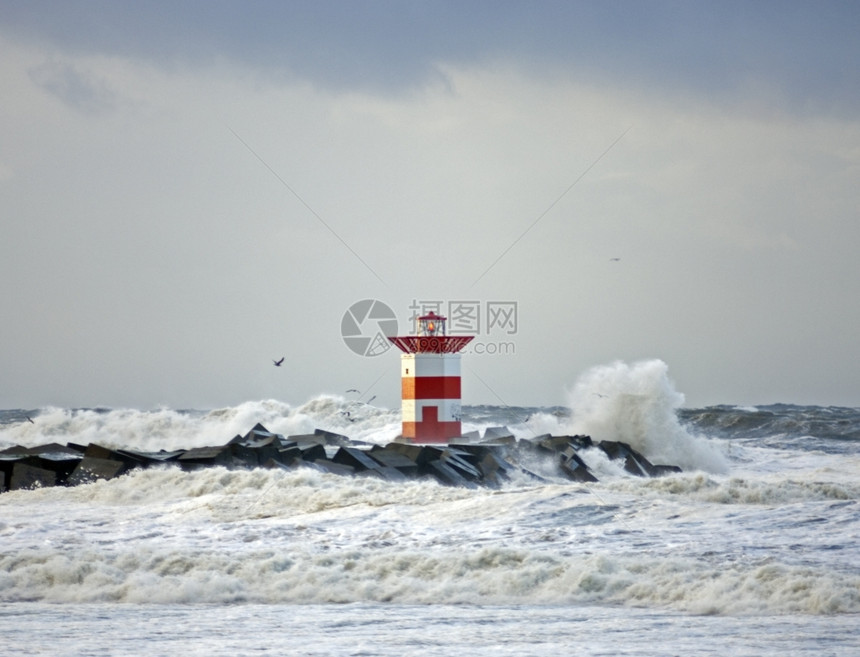 海浪冲入混凝土码头导致灯塔在暴风雨的一天狂大海鸥港口支撑图片