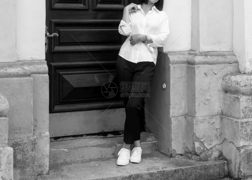 靠近入口屋年轻女子在旧楼木门附近摆姿势图片