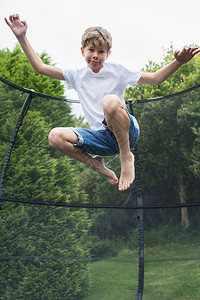 男生中空射花园Trampoline的男孩复制弹跳背景图片