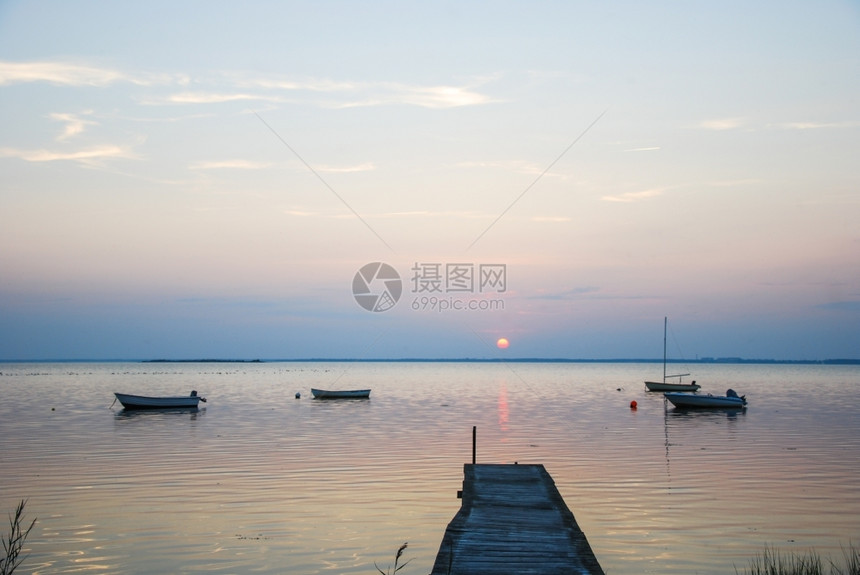 美丽的古老木制小码头在黄昏时一个宁静的海湾内停泊着小船只景观划图片