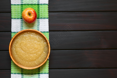 乡村健康伴奏木碗中自制苹果酱用然光照黑木头上方图片
