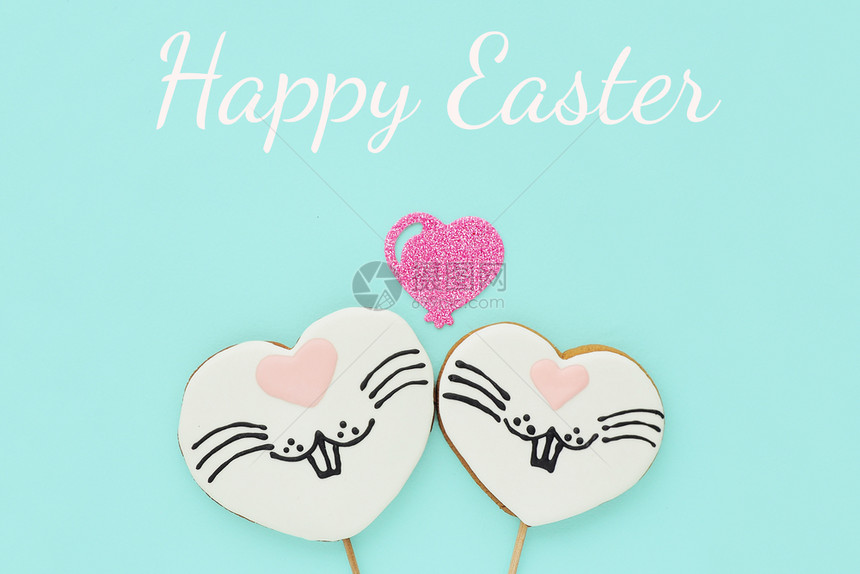 动物欢乐复活节贺卡两个姜饼干在一根棍子上的两杯姜饼以心脏的形状画着兔子脸和闪亮的心在蓝色背景上假期投标图片