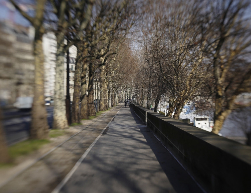 路面巴黎塞纳河旁的一条人行道延伸至距离注意这个图象显示镜头模糊的影响与一个Lensbaby相伴而来城市的阴影图片