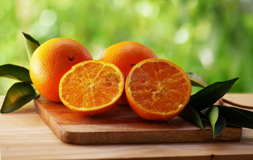 素食主义者圆圈绿色背景上叶子的新鲜橙色水果甜点图片
