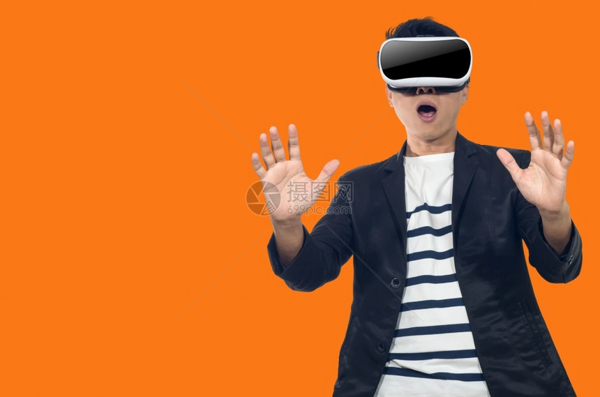 视频一种有虚拟现实眼镜的年轻人站在橙色背景的室内青年男子带着虚拟现实眼镜的年轻男子虚拟图片