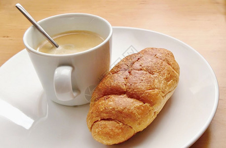 一种美味的大陆早餐咖啡和新鲜羊角面包在白色盘子上图片