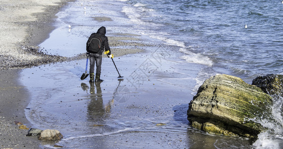 清除ODESSAUKRAINE01257带金属探测器的人在冬季清晨的海滩上寻找宝藏在海滩上的一个宝藏猎人闲暇冬天背景