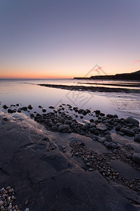 玻璃状的日落时金梅里奇湾在英国格兰多尔塞海岸滩安详图片