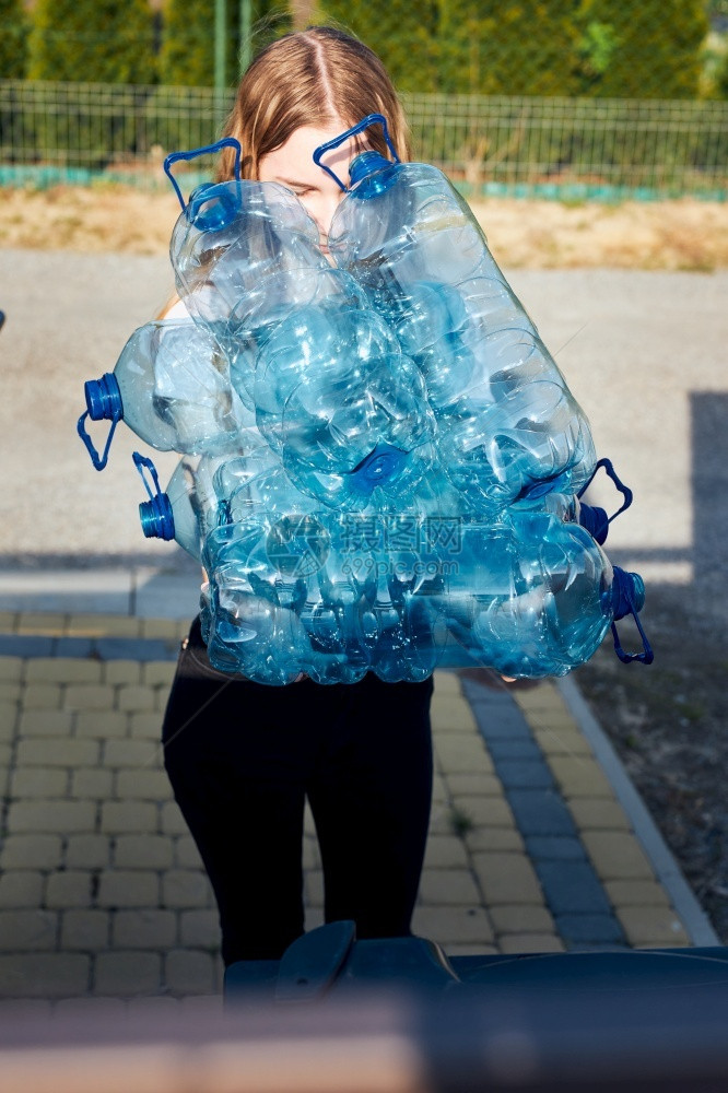 生态的浪费女将废旧塑料水瓶扔进垃圾桶的年轻妇女把空用塑料瓶丢弃在垃圾桶里收集塑料废物以回收以便回收塑料污染概念和太多塑料废物图片
