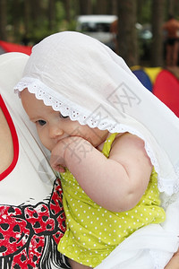 女孩常设披风小婴儿在白色的毛发上小婴儿在白色的花纹上放在她母亲的手里图片