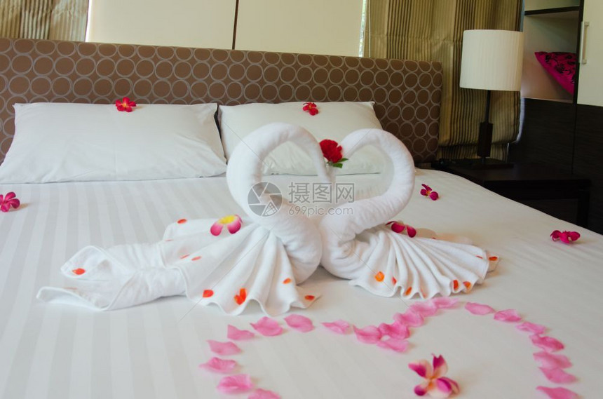 室内卧天鹅毛巾和床上的兰花酒店房间对夫妇来说是浪漫的内部枕头美丽图片