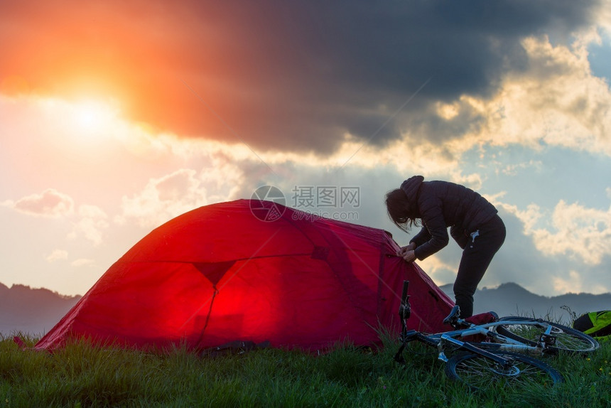 年轻的旅游运动妇女带着帐篷和自行车在山地风景中旅行背是太阳AC54970附件晚上户外活动图片