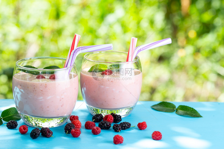 靠近的木环桌是莓贝里香水或酸奶用圆玻璃杯和稻草装着酸奶带树干面板的是浆果Berry冰条或酸奶圆形的甜点图片