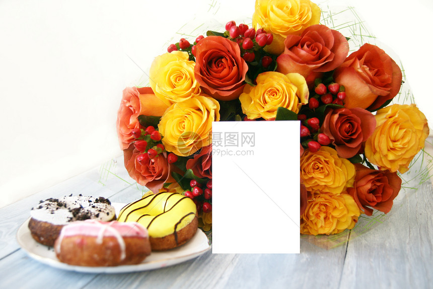 8日一大束美丽的花由黄色和红橙玫瑰浆果组成放在灰木背景上紧靠白瓷板盘上面有三张多色甜圈的明信片布局挂在花束的背景上灰色下一个图片