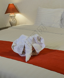 干净的放松在泰国式旅馆卧室的白床上用大象形状的白毛巾色图片
