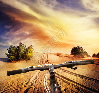 阳光日落清除戏剧天空下沙漠地背景的自行车把沙漠地背景的自行车把图片
