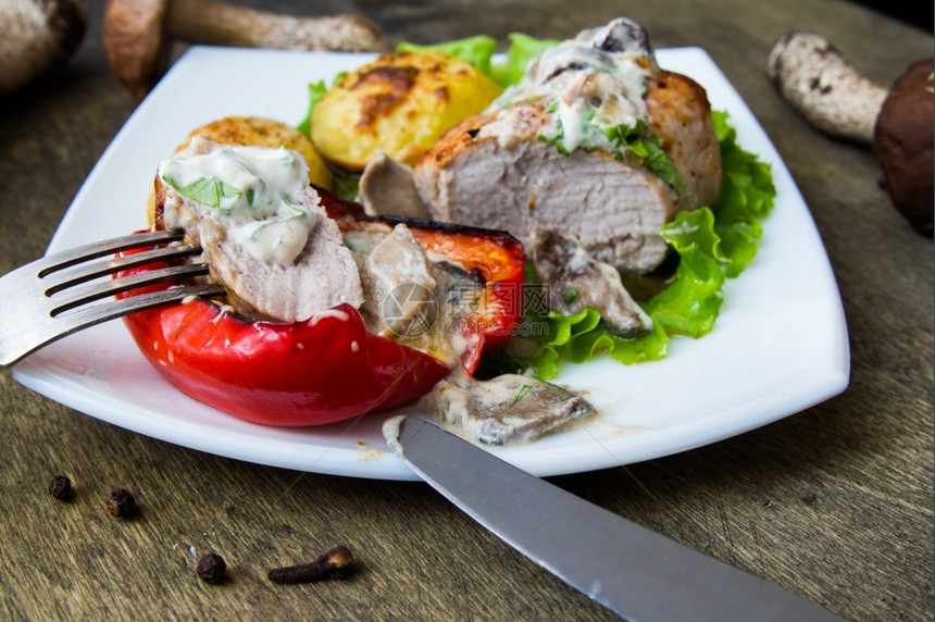 食物蔬菜猪肉牛排加烤土豆和白盘蘑菇酱烘烤的图片