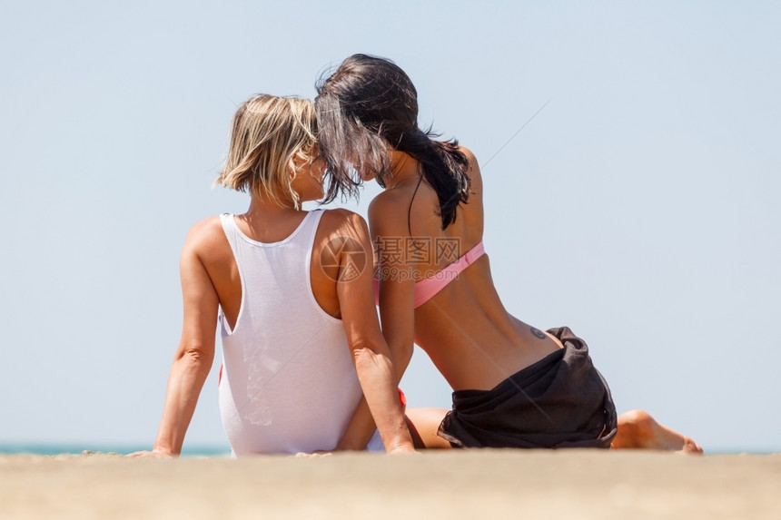 夏天幸福两个年轻女孩在海边滩聊天很愉快两个年轻女孩在海边的滩上闲聊笑声图片