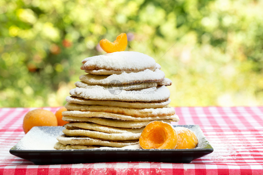 面包店餐桌上有杏子和冰糖的煎饼红桌布天然背景传统菜盘饭桌上有杏子和冰糖的煎饼午餐蛋糕图片