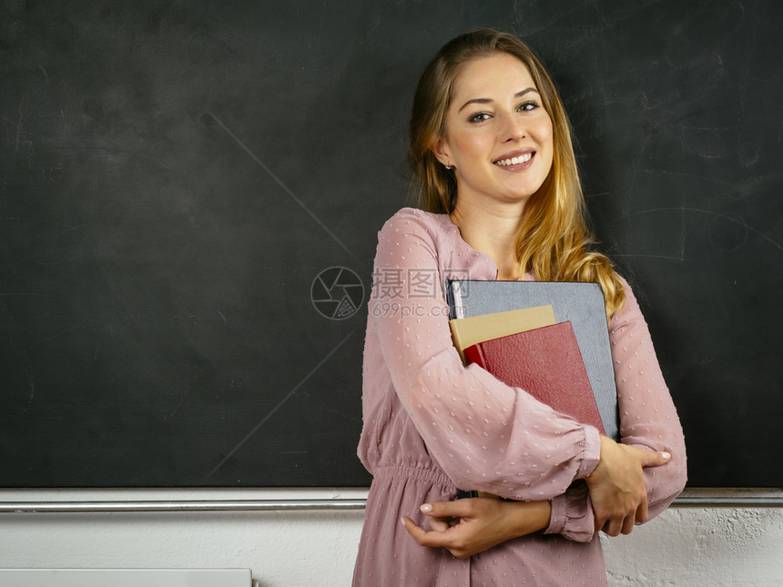 学习保持校照片来自一位美丽的年轻学生在黑板前拿着书籍的照片图片