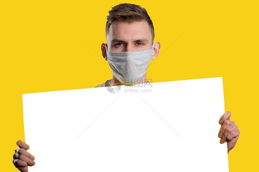 医疗的纸面具戴用口罩的年轻人展示白皮书海报看着黄色背景的相机图片