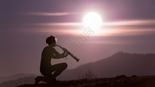 女孩喇叭乐器日落时紫色天空中的萨克斯播放器图片