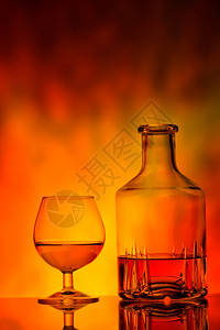 鸡尾酒液体黑色的玻璃和干邑酒瓶在火背景上玻璃和干邑酒瓶图片