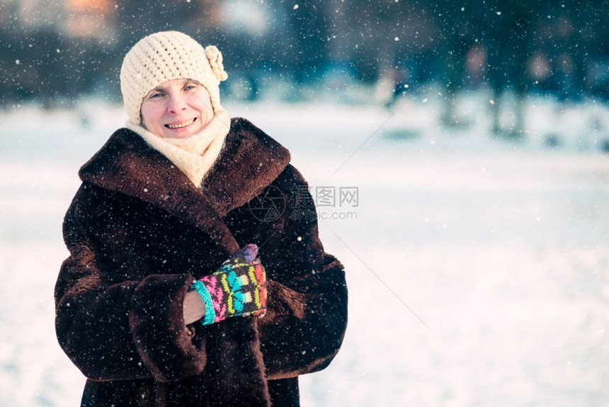 淑女一位带着羊毛帽围巾和彩色手套有雪背景的微笑成年老妇女冬季肖像优雅有色图片