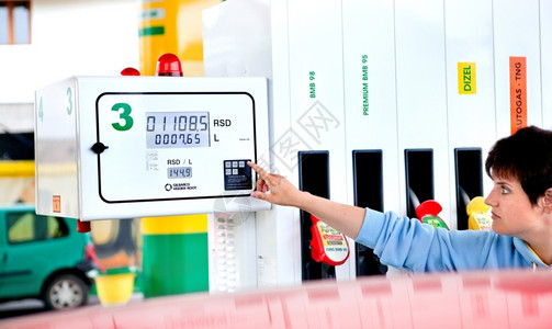 活力红色的喷嘴女子经营汽车加油站太阳气泵图片