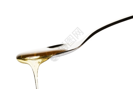 蜂蜜从勺子上掉下来蜂蜜从勺子上落到白底黄色的银器美味图片