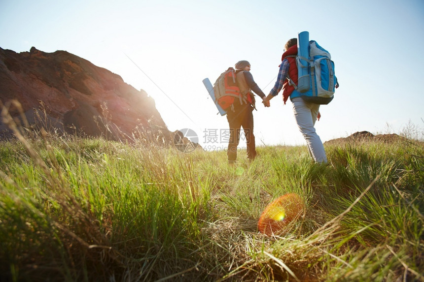 年轻旅游情侣的浪漫冒险低角度的男女上山高举手向徒步道路明光照亮阳上坡户外草图片