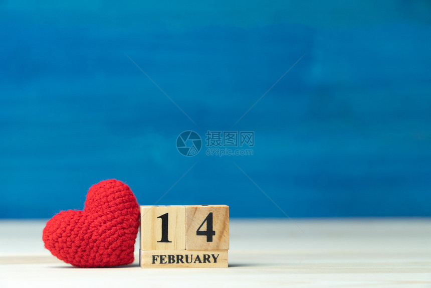 2月14日情人节的木桌和蓝底定在2月14日的木板和蓝色背景上把情人节的概念手把铁线红心放在木块日历旁天抽象的假期图片