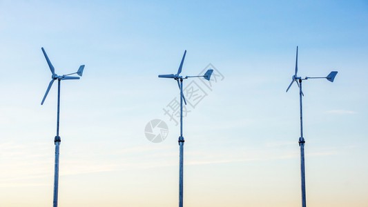 日落时三台风力涡轮机工业的螺旋桨光线图片