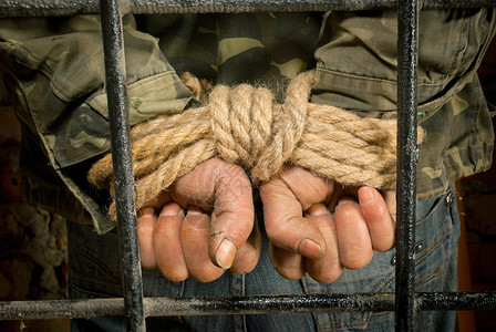 安全人用手捆绑在铁笼后面的绳子人类惩罚图片素材