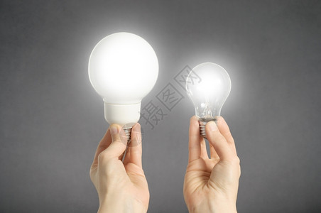 力量电两只手握着发光灯泡解决方案图片