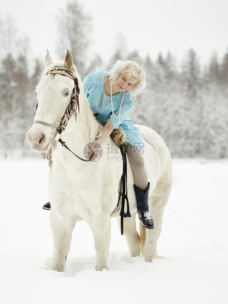女孩辔身着蓝裙子骑白马的迷人女吸引的图片