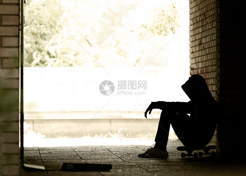 青少年不良习惯孤独的少年青坐在黑暗的门道上穿着汗衫和兜帽图片