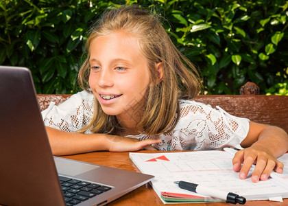 学校金发女郎10岁的漂亮少年学生在计算机上学习的幸福和快乐的图片