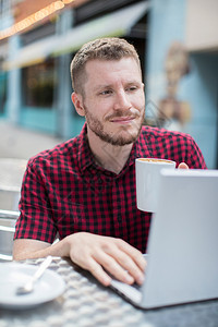 沟通服装正面外门咖啡厅的年轻人在笔记本电脑上工作图片