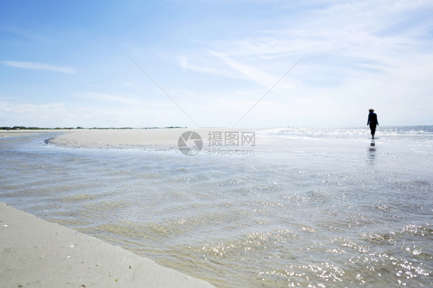 在沙热带海滩潮汐和远方人的浅滩悬光影中提取浅海水对面进行部分反省从低角度观察海景情况暑假概念太阳夏天区图片