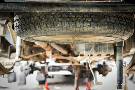 当一个轮胎漏气或破损时汽车在腹部下的橡胶零配件将发生改变车辆什么时候库背景图片
