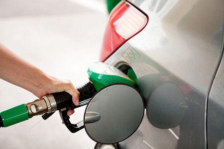 加减乘数手臂乙醇水平的在加油站为汽车的女乘数背景