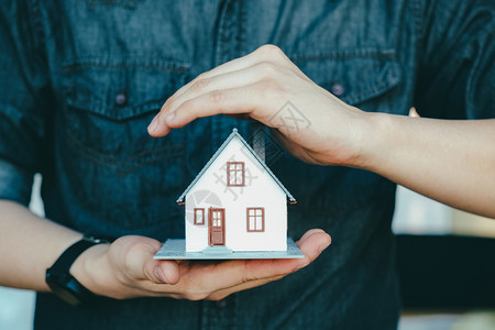 建筑学生意人手握着救小房子保险的屋模型抢救小房子保险监护人家图片