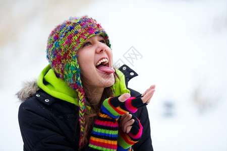 美丽的坠落一个十几岁的女孩试图捕捉落下的雪花在她舌头上肖像背景图片